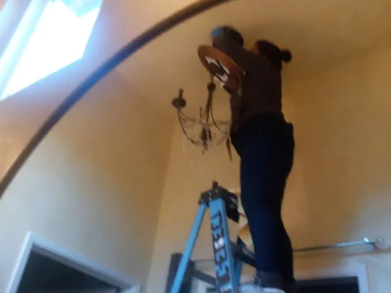 Electrician installing a chandelier in a Lloyd Harbor residence